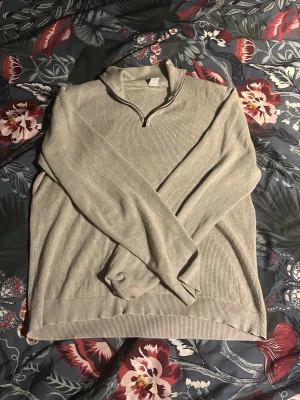  half zip tröja - Säljer en beige ribbad tröja med half zip och hög krage. Tröjan har långärmade ärmar och är gjord i ett mjukt stickat material som är perfekt för kyliga dagar. Enkel och stilren design som funkar till många olika outfits.