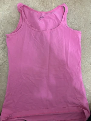 Rosa linnetopp från Skill - Säljer en enkel och snygg rosa linnetopp från Skill i storlek S. Toppen är ärmlös med klassisk rund halsringning och tillverkad i mjuk bomull. Perfekt att matcha med jeans eller shorts för en chill look.