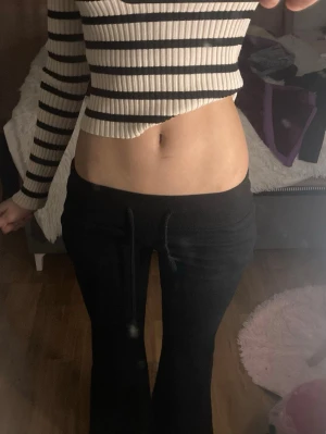 Svarta bootcut mjukisbyxor med snörning - Säljer ett par svarta mjukisbyxor med bootcut-snitt och snörning i midjan. Byxorna har en skön och loose passform, perfekta för chill dagar. Materialet är mjukt och stretchigt, vilket gör dem riktigt bekväma att ha på sig.