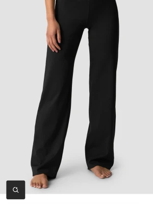 Svarta wide mjukisbyxor - Svarta träningsbyxor med wide passform och rak siluett. Byxorna har en enkel design utan synliga detaljer och är tillverkade i ett mjukt material som ger en skön känsla. Perfekta för chill dagar och avslappnade outfits. Helt oanvända