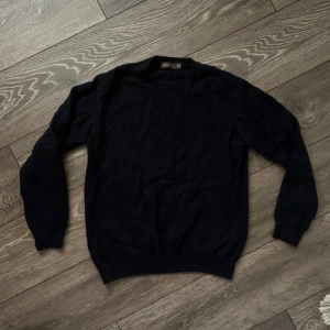 Marinblå kashmirtröja från Oscar Jacobson - Mjuk och stilren marinblå tröja från Oscar Jacobson i kashmir. Rund hals och ribbade muddar vid ärmslut och nederkant. Perfekt för dig som gillar klassisk och enkel design med lyxig känsla. Passar dig som vill ha en skön och snygg tröja till hösten och vintern. Lite nopprig