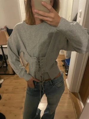 Grå sweatshirt med snörning i midjan - grå sweatshirt med cool snörning i midjan, bra skick! 