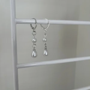Silvriga örhängen med pärlor - Snygga silvriga örhängen med hängande vita pärlor i droppform och rund form. Perfekt för dig som gillar stilrena och eleganta smycken med en modern touch. Lätta att matcha med olika outfits och ger en classy vibe. Handgjort