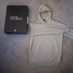 Kashmir hoodie från Oscar Jacobson - Säljer en stilren beige hoodie från Oscar Jacobson. Tröjan har en klassisk design med långa ärmar och en bekväm huva. Perfekt för en avslappnad och snygg look. 