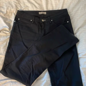 Svarta jeans från Acne Studios - Snygga svarta jeans från Acne Studios med klassisk femficksdesign och raka ben. Jeansen har silverfärgade nitar och knapp, samt en svart läderpatch med Acne Jeans-logga bak i midjan. Storlek är 29/34