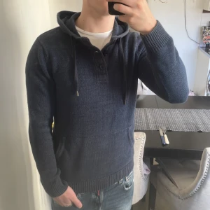 Blå stickad hoodie - Säljer nu denna riktigt feta stickade blå hoodien med knappar upp mot kragen. Inga defekter. Storlek xs men sitter mer som S. Modellen är 180, 72kg och använder normalt S-M.