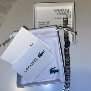 Silverfärgat armband från Lacoste - Stilrent armband från Lacoste i silverfärgat metall med länkdesign och ingraverad krokodil på spännet. 🐊Armbandet har en cool texturerad yta på vissa länkar som ger extra edge. Kommer i original ask och tygpåse med Lacoste-logga. Autenticitetsbevis skickas via PM, skriv vid frågor/funderingar😁