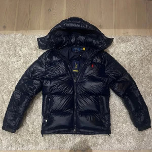 Mörkblå pufferjacka från Polo Ralph Lauren - Säljer nu denna sprillans nya Ralph lauren jacka🤩 Jackan är köpt på Ralph Laurens hemsida för 6000kr, och kommer med alla orginal tags samt ett digitalt kvitto💫Hör av er vid funderingar!