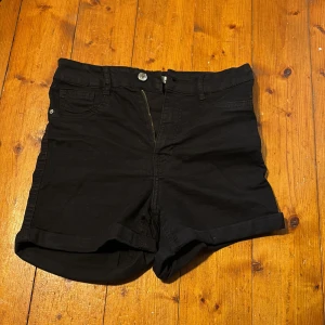 Svarta shorts med fickor - Säljer ett par svarta shorts. De har uppvikta benslut, knapp och dragkedja framtill samt bälteshällor. Mycket använda men ändå väldigt bra skick.