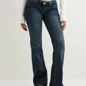 Mörkblå bootcut jeans med rå kant - Snygga mörkblå jeans med bootcut passform och rå, fransad midja. Jeansen har klassiska fickor fram och bak. Dom e från Nelly, säljer då dom blivit för små. Använd några få gånger så bra skick!