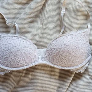 Vit spets-bh från Intimissimi - Säljer en vit bh från Intimissimi med vacker spets och justerbara axelband. Bh:n har fina spetsdetaljer över kuporna och längs kanterna, samt hak- och hyskknäppning bak. Perfekt för dig som gillar romantiska och feminina underkläder. Lite nopprig men syns inte på det hela, därför det lite billigare priset. Ny pris: 500kr