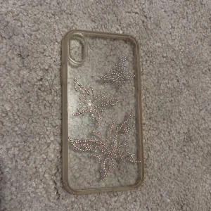 iPhone XR Skal med Strassfjärilar - Snyggt genomskinligt skal till iPhone XR med glittrande strassfjärilar. Den har en liten missfärgning och några stenar har lossnat men inget man lägger märke till!🩷