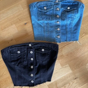 Jeanstoppar - Två snygga bandeau tubtoppar i jeansmaterial, en i klassisk blå och en i svart. Silvriga knappar, fickor och smockad rygg som ger stretch, båda för 60kr:)