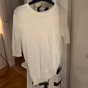 Vit stickad tröja från Zara - En stilren vit stickad tröja från Zara med rund halsringning och kortare ärmar. Tröjan har en mjuk känsla och ribbade muddar vid ärmslut och nederkant (sitter även tajtare där) tröjan är använd ett par gånger men väldigt bra skick.