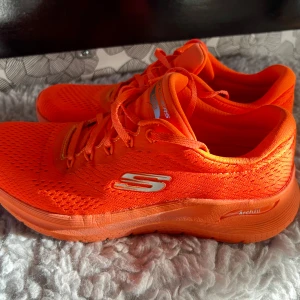 Orange sneakers från Skechers Arch Fit - Säljer ett par riktigt snygga och färgstarka orange sneakers från Skechers Arch Fit. Skorna har ventilerande mesh-tyg, snörning och en bekväm sula med Arch Fit-teknologi. Perfekta för dig som vill sticka ut och ha sköna skor till vardags eller träning. Har gått max 10 km. Skechers storlekar upplevs stora, jag har 40-41 men 39 i Skechers.