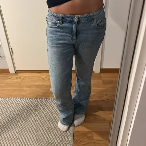 Ljusblå bootcut jeans med låg midja - Säljer ett par ljusblå jeans med låg midja och bootcut passform. Klassisk femficksmodell. Jeansen har en avslappnad passform och är perfekta för en vardagslook.