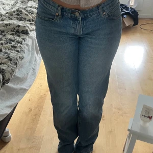 Blå straight jeans från Abrand - Snygga blå jeans från Abrand med klassisk femficksdesign och brunt läderpatch på bakfickan. Modellen är straight med normal passform och hög midja. Jeansen är tillverkade i robust denim med orangea sömmar för en cool vintagekänsla.