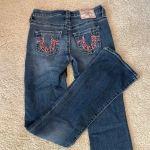 True Religion Becca Bootcut Jeans - Snygga blå jeans från True Religion, modell Becca MidRise Bootcut. De har klassisk bootcut-passform och coola bakfickor med rosa broderad logga. 