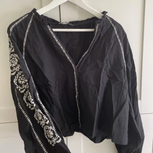 Svart broderad blus från Zara - Svart blus från Zara med vita broderade detaljer längs ärmar och sömmar. Skrynklig för att den legat nerpackad. Står storlek L men passar även mig som har M. Använt men bra skick - inga defekter. 