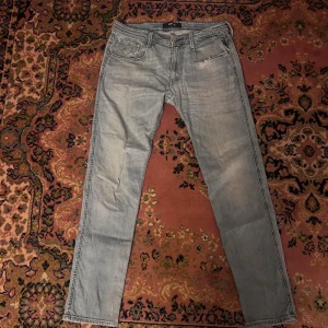 Replay Anbass  ljusblå jeans, storlek 34/32 - Säljer ett par ljusblå jeans från Replay i storlek 34. Klassisk femficksmodell med raka ben och snygga slitningar. Jeansen har normal passform och är tillverkade i mjukt denimtyg. Perfekta för dig som gillar en avslappnad och stilren look. Midja 41cm längd 101cm (45)