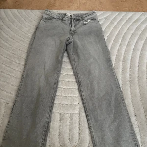 Grå raka jeans - Säljer ett par grå jeans med klassisk rak passform. Jeansen har fem fickor och stängs med dragkedja och knapp. Perfekta för en avslappnad och stilren look. Använda fåtal gånger och petite längd. 