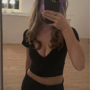 Svart croppad v-ringad topp - Snygg svart croppad topp med djup v-ringning och korta ärmar. Perfekt till exempel till fest. Säljer då den inte kommer till användning 🖤