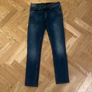 Tiger of Sweden blå jeans straight fit - Snygga blå jeans från Tiger of Sweden med klassisk femficksdesign och raka ben. Jeansen har orange kontrastsömmar, normal passform och mellanblå tvätt. Perfekta för dig som gillar stilrena och tidlösa jeans.