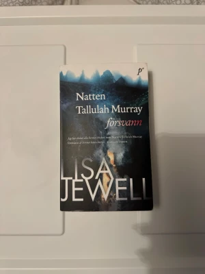 Natten Tallulah Murray försvann - En spännande pocketbok med titeln 'Natten Tallulah Murray försvann' av Lisa Jewell. Omslaget är mörkt med blå och svarta toner och visar en mystisk skogsscen. Perfekt för dig som gillar nagelbitande thrillers och familjehemligheter.