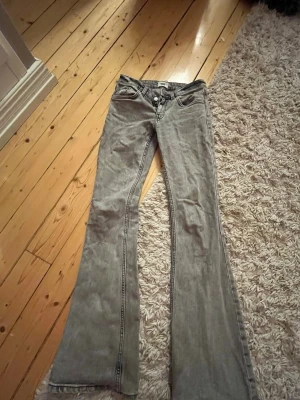 Grå bootcut jeans från 157 - Snygga grå bootcut jeans från 157 med låg midja. Jeansen har klassisk femficksdesign och är tillverkade i ett mjukt bomullsmaterial med lite stretch. Perfekta för dig som gillar en retro och avslappnad look.