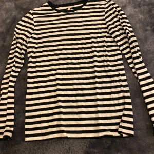 Randig långärmad tröja från Only - Säljer en superfin randig tröja från Only i storlek 146/152. Den är svart och vit med långa ärmar, perfekt för både skola och fritid. Tröjan är i bra skick och gjord av mjukt material som är skönt mot huden. Passar perfekt till jeans eller kjol för en avslappnad look!