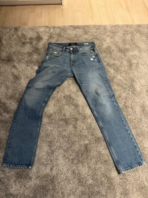 Blå Rocco jeans från Replay - Säljer ett par blå Replay Rocco jeans i klassisk femficksmodell. Jeansen har slitna detaljer och raka ben, med en snygg tvättad look. Perfekta för dig som gillar en avslappnad men stilren vibe. W28 L30, skriv om du har frågor och skicka gärna bud!