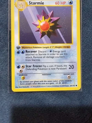 Starmie #64 1st Edition  - Säljer ett Starmie Pokémonkort från Base Set, nummer 64/102. Kortet har en färgstark illustration med lila, gul och röd stjärnformad design. Text och effekter på engelska. Perfekt för samlare eller Pokémonfans.