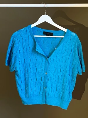 Blå kortärmad kofta med knappar - Snygg blå kofta med korta ärmar och knäppning framtill. Stickat mönster ger en trendig look. Köpt från Zara, aldrig använd💙