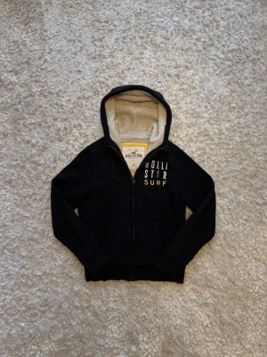 Hollister fodrad hoodie svart - Snygg hoodie/cardigan från hollister, den är fodrad vilket gör den varm. Använd men i gott skick.  Mått: Längd: 67 Bröstvidd: 55 Ärm: 70 