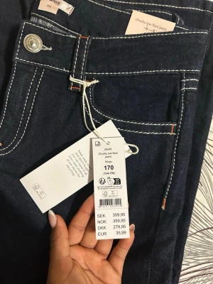 Chunky low flare jeans  - Mörkblå chunky low flare jeans från Gina Tricot med kontrastsömmar och klassisk femficksdesign. Jeansen har låg midja och utsvängda ben 