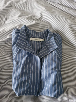 Blåvit randig skjorta från inwear - Kortärmad skjorta från Inweari blått med vita ränder. Skjortan har klassisk krage och raka ärmar, tillverkad i mjuk bomull som känns skön mot huden. Perfekt för en avslappnad och stilren look. 