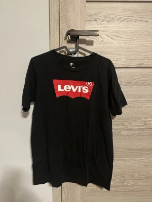Levi's t-shirt svart och grå - Två klassiska t-shirts från Levi's, en i svart och en i grått, båda med det ikoniska röda Levi's-logotrycket på bröstet. T-shirtsen har rund hals och korta ärmar, perfekta för en avslappnad och stilren look. 