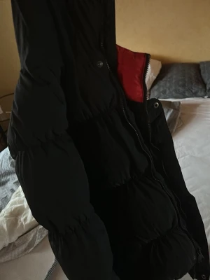 Säljer denna Jordan vinterjacka i god skick! - Säljer en svart Jordan pufferjacka med quiltad design och röd insida. Jackan har dragkedja framtill och en oversized passform som ger en riktigt chill vibe. Perfekt för kalla dagar när du vill hålla dig varm och ändå se snygg ut.
