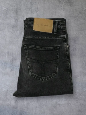  Tiger of Sweden Jeans - Snygga svarta jeans från Tiger of Sweden med klassisk femficksdesign och en stilren läderpatch bak i midjan. Jeansen har raka ben och är tillverkade i ett mjukt bomullsmaterial med en mörk tvätt som ger en cool look.