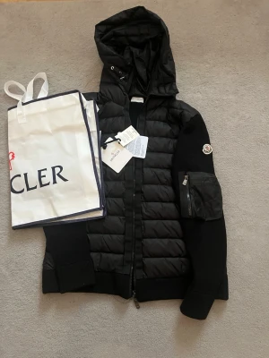 Moncler Cardigan  - Svart Moncler cardigan – Storlek XL men passar även jätte bra för storlek L och M Cardiganen är svart och har Monclers klassiska logga på ärmen som har NFC. Skicket är helt nytt och alla lappar finns kvar. För fler frågor är det bara att höra av sig! ❤️