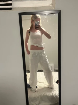 Vita linnebyxor med snörning - Säljer ett par vita linnebyxor med avslappnad passform och snörning i midjan. Byxorna är raka i modellen och har en luftig känsla, perfekta för varma dagar. Materialet är linne vilket gör dem svala och bekväma.