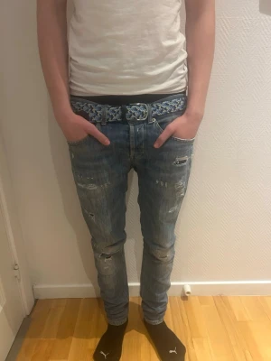Dondup Jeans - Säljer ett par blåa slim fit jeans från DONDUP med slitningar och hål på benen. Jeansen har klassisk femficksdesign och en något tvättad look. Perfekta för en avslappnad och trendig stil.    //Längd 101 CM//Midja 41 CM