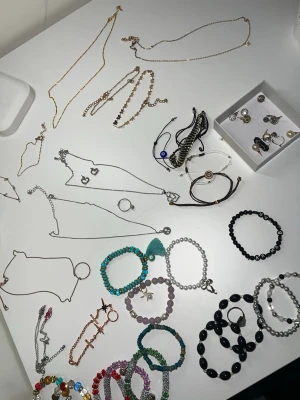 Stort smyckespaket med armband & halsband - Säljer ett mixat smyckespaket med flera halsband, armband, örhängen och ringar i olika färger och former. Innehåller bland annat silverfärgade hjärthalsband, pärlarmband, färgglada stenar, örhängen och ett öga-armband. Det är både smycken från ur & peen, utomlands och shien