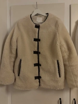 Beige teddyjacka med svarta detaljer - Säljer en beige teddyjacka från H&M. Nypris: 559kr, använd fåtal gånger. Har en i storlek S och M. Hör av er om vilken storlek ni vill köpa! Pris kan diskuteras 