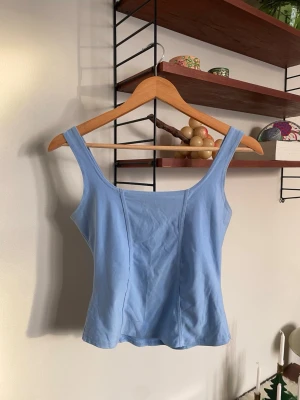 Vintage korsettlinne  - Vintage blått linne med fyrkantig ringning. Ger snygg figur. Korsettliknande siluett. Toppen är i ett mjukt material som passar perfekt till sommaren eller som ett basplagg under en kavaj eller kofta. Strl S. Fint skick!   ✨ Se även mina andra annonser, 3 för 2 på allt! ✨