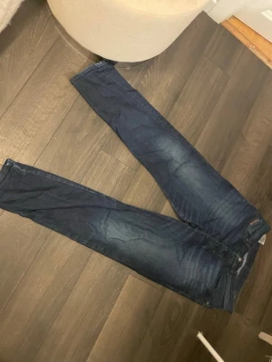 Mörkblå disel jeans herr - Snygga mörkblå jeans från disel , modell Anbass. Klassisk femficksdesign med raka ben och diskreta slitningar. Jeansen har en normal passform och är tillverkade i mjukt bomullsjeansmaterial. Perfekta för en stilren och avslappnad look.