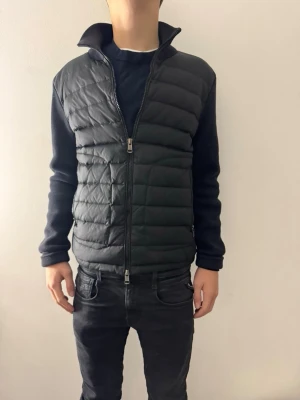 Svart Moncler cardigan  - Moncler cardigan – strl S (äkta) Säljer en äkta Moncler cardigan i storlek S. Svart modell, men nästan mörkblå,  Den är i bra skick, väl omhändertaget och utan större slitage. Dragkedja och detaljer fungerar som de ska.                                                                        Hör av dig vid frågor eller om du vill ha fler bilder 😊