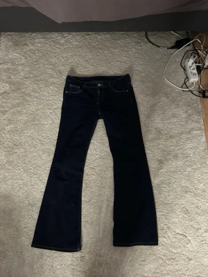 Mörkblå bootcut jeans - Snygga mörkblå bootcut jeans med klassisk femficksdesign och kontrastsömmar. Jeansen har utsvängda ben och normal midja, perfekta för en trendig och avslappnad look. Tillverkade i ett mjukt denimtyg som sitter skönt hela dagen. Strl 44 men passar 42, jag är 173 dom passar perfekt i längden. 