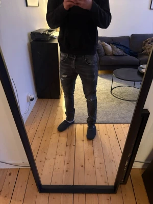Mörkgrå slitna dondup jeans George  - Säljer ett par mörkgrå slim fit jeans med slitningar och hål på låret och knät. Jeansen är från dondup med modellen George i storlek 35. Fåtal gånger använda