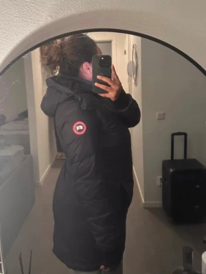 Svart dunjacka från Canada Goose - Säljer en svart dunjacka från Canada Goose med huva och klassisk logotyp på ärmen. Jackan är lång, har dragkedja framtill och är perfekt för kalla vinterdagar. Storlek L men känns mer som en M Använd ett par gånger Köpt på Länna Sport Nypris 10 500kr